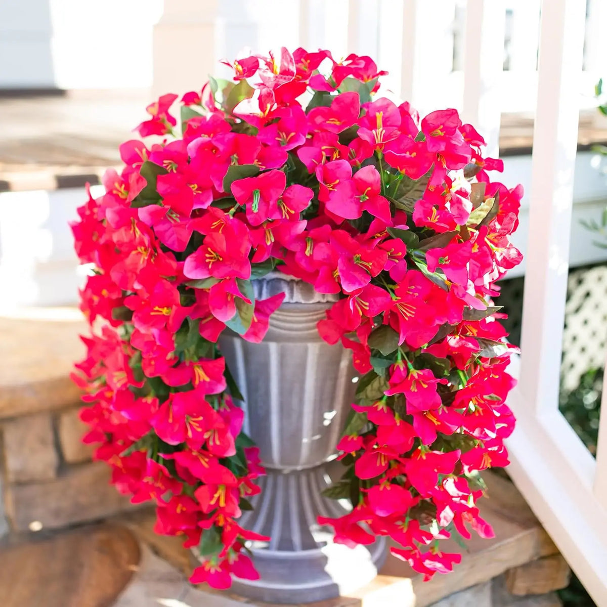 A vibrant arrangement of artificial bougainvillea vine garland in bright pink and red flowers displayed on a pedestal.