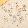Silver number candles spelling out '192354' scattered on a light background with gold confetti.