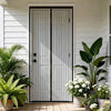 A modern black magnetic automatic screen door curtain installed in a white siding exterior with green plants.