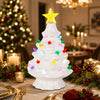 A white ceramic Christmas tree decorated with multicolor LED lights sits on a table surrounded by festive greenery and gold a