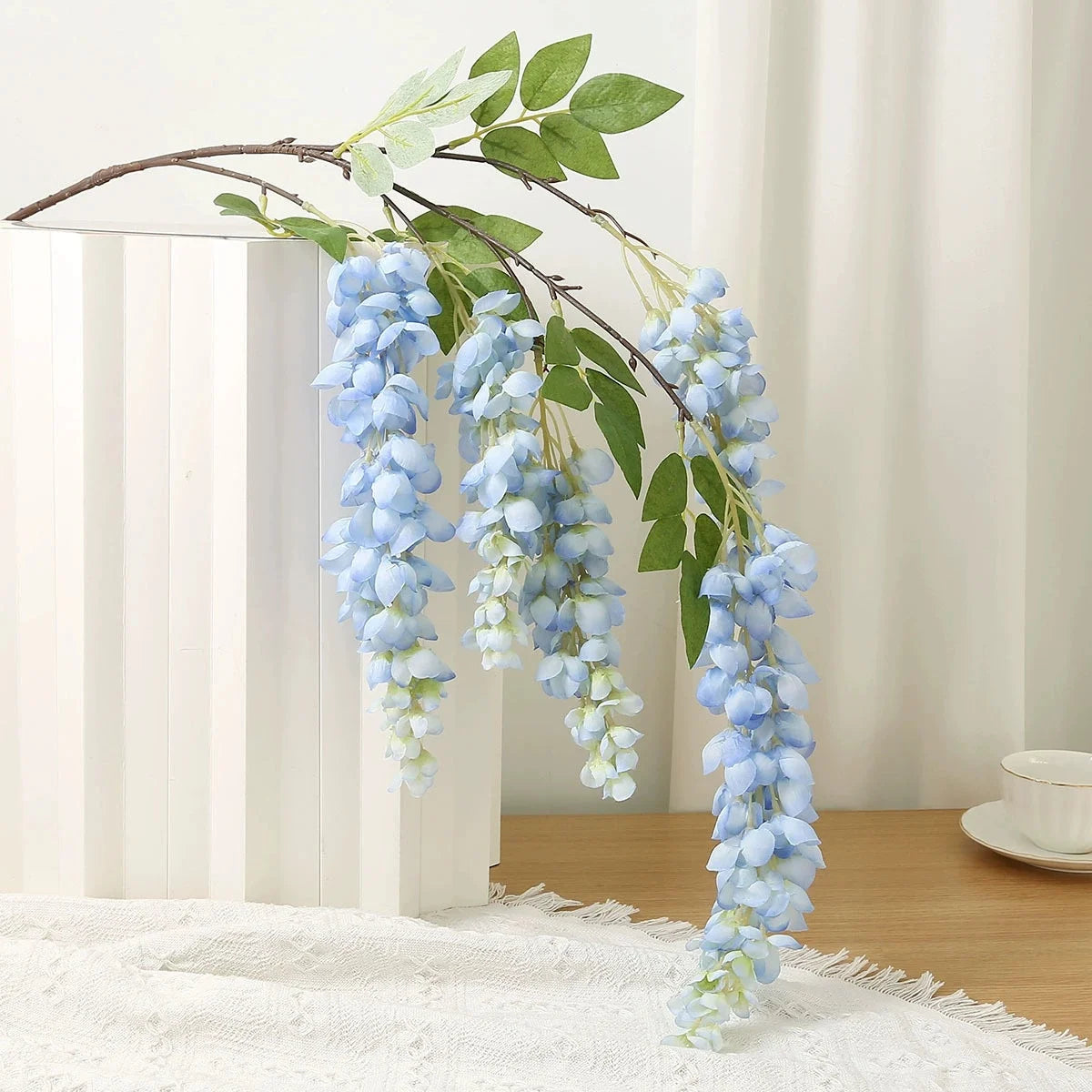 Artificial wisteria hanging vine with blue silk blooms on a branch