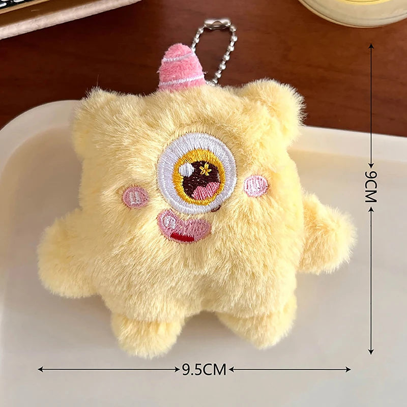 A yellow fuzzy plush monster with pink accents and a large eye, shown against a white background.