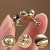 A vintage brass frog statue ornament is held between fingers, showing detailed texture and craftsmanship.