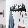 A black metal mountain forest silhouette key holder with hooks mounted on a white wall.