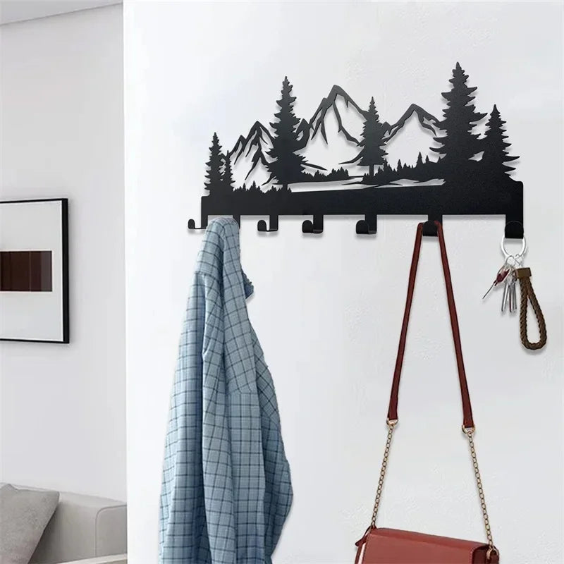 A black metal mountain forest silhouette key holder with hooks mounted on a white wall.