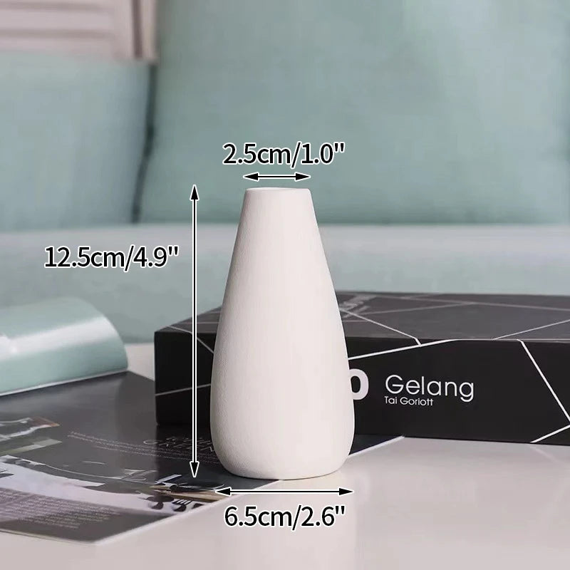 A white ceramic bud vase is shown on a dark surface with dimension lines indicating its size.