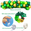 A balloon arch garland made of green and gold foil balloons and tinsel curtain with a hand demonstrating the balloon decorati