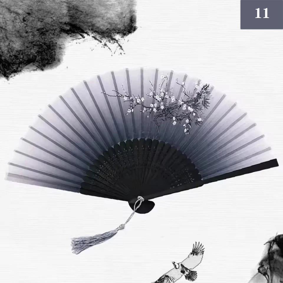 A black vintage silk bamboo folding hand fan is shown open, with delicate white flowers visible near the top.