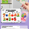 A hand holds a magnetic alphabet and number learning set featuring fruit shapes and numbers on a white board.