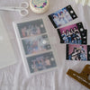A photo album with transparent card holders and several printed photos is displayed on a white cloth.
