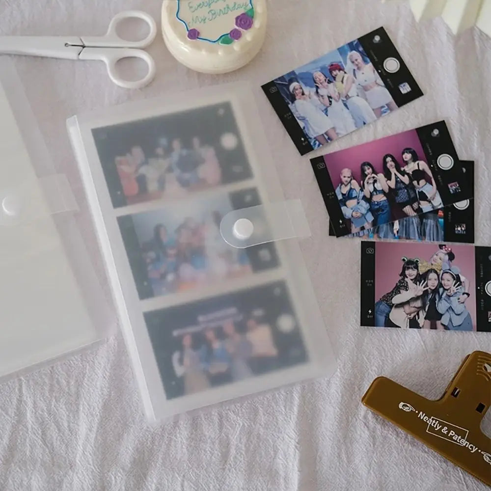 A photo album with transparent card holders and several printed photos is displayed on a white cloth.