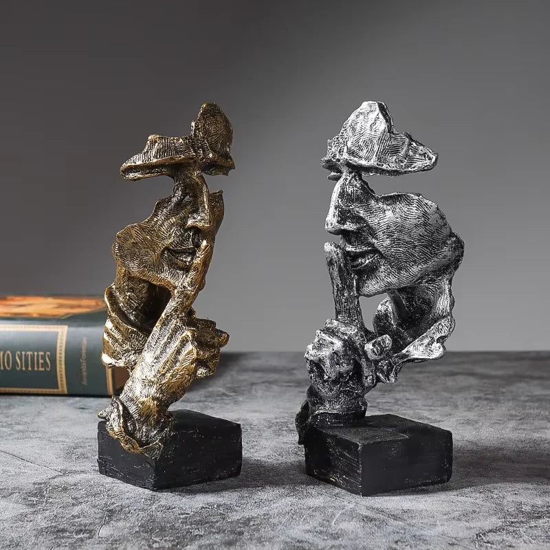 A set of three resin figurines depicting figures with large leaves or foliage, displayed on a dark surface.
