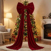 A deep red velvet Christmas tree topper bow with long streamers displayed in a festive holiday setting.