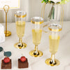 Four elegant gold-rimmed champagne flutes filled with pale yellow liquid are displayed on a white marble surface.
