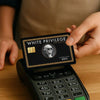 A hand holds a white privilege exclusive credit card with a silhouette of a person and a gold embossed design on a black card