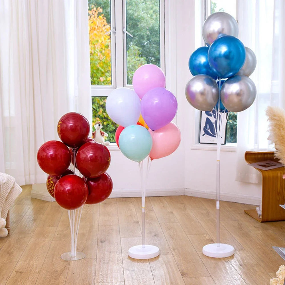 A display of various colored balloons, including pink, purple, blue, and silver, arranged on stands for party decorations.