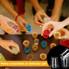 Hands are holding and pouring colorful liquid into reusable plastic shot glasses for a party or gift.