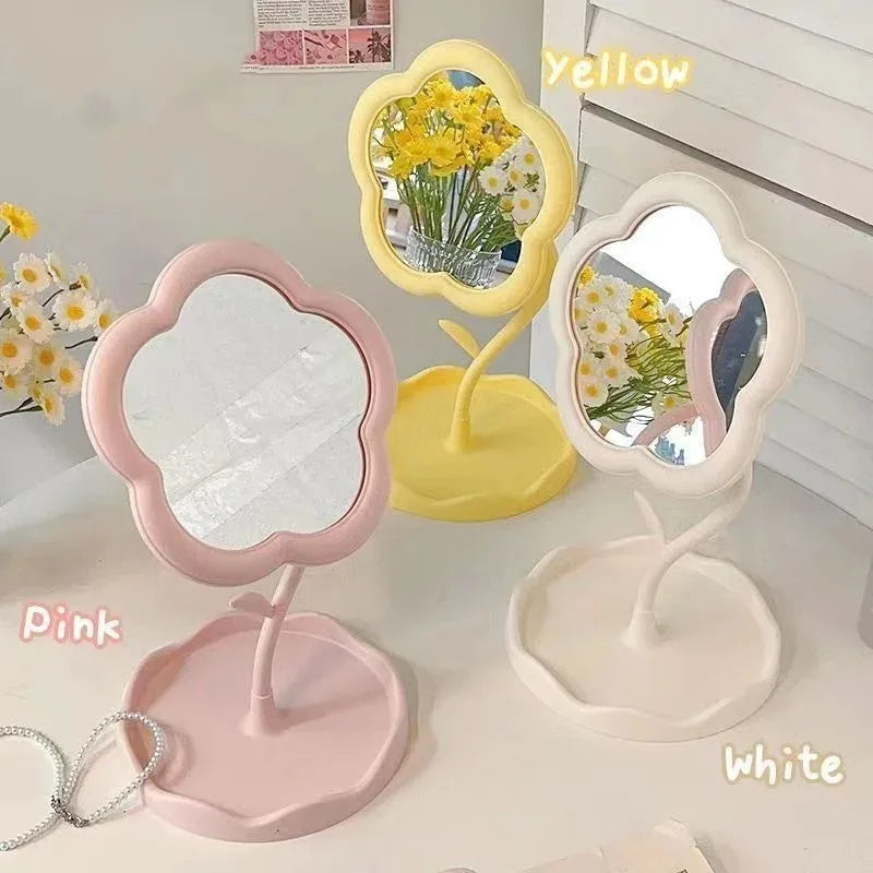 A set of three floral decorative desktop mirrors in yellow, pink, and white on a white surface.