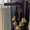 Decorative metal wind chimes hanging from a dark purple door handle.