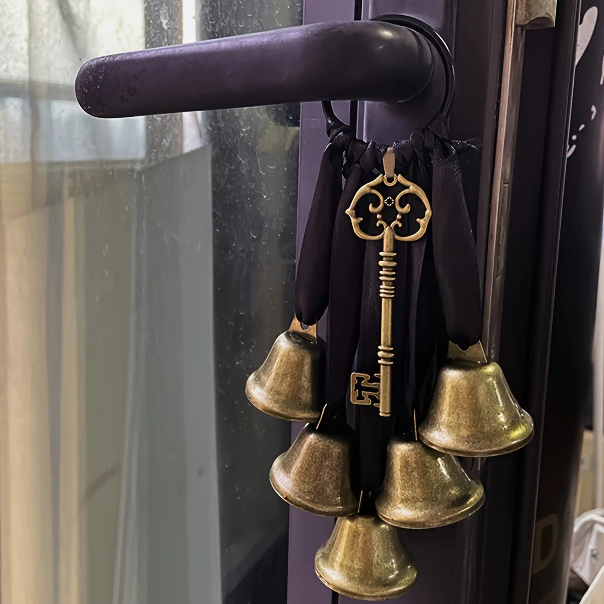 Decorative metal wind chimes hanging from a dark purple door handle.