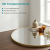 A round, gold-edged mirror reflects a room interior and decorative objects on a wooden surface.