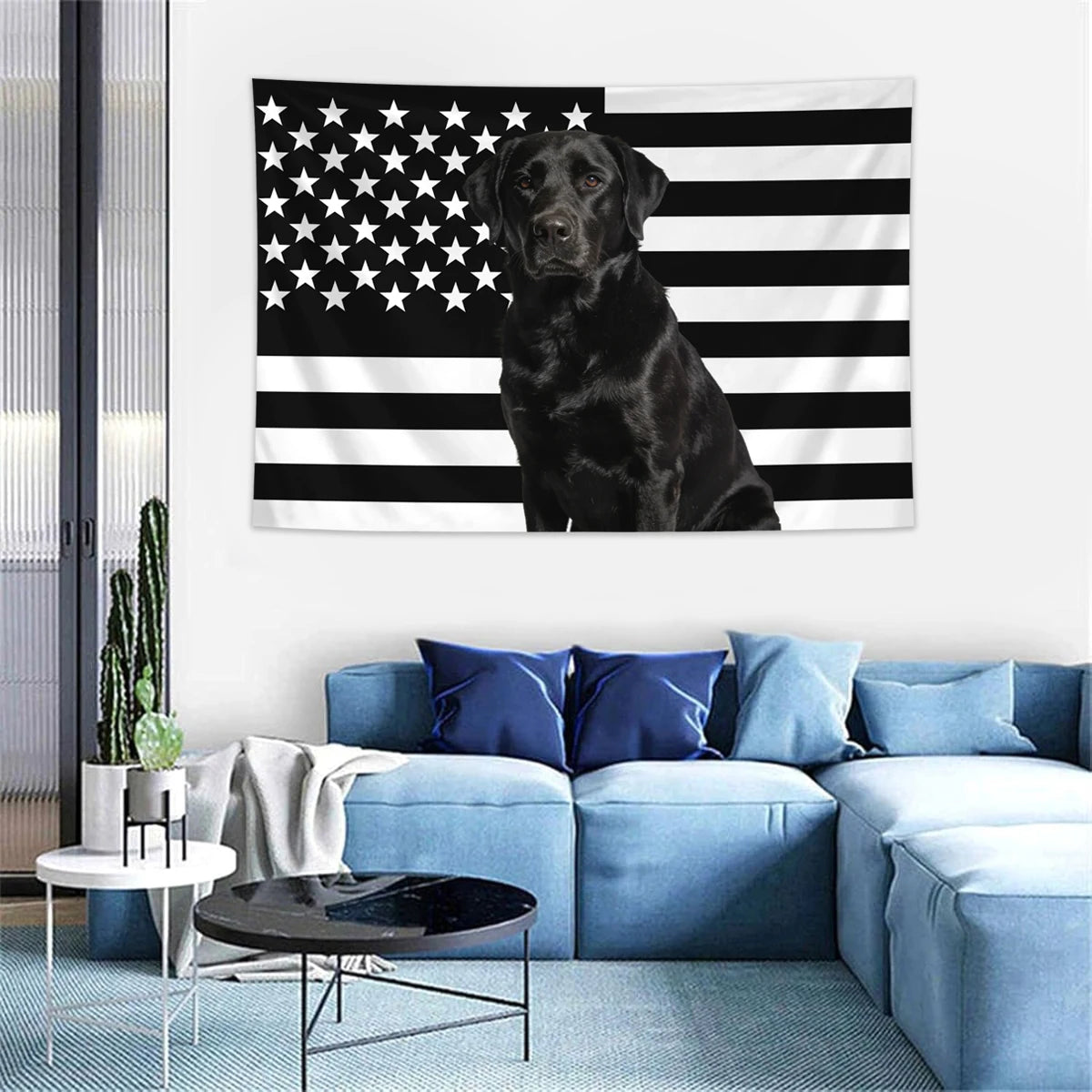A dark dog is centered on a black and white striped American flag tapestry displayed on a white wall.