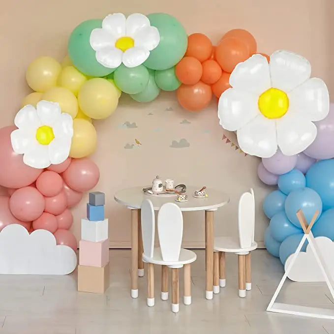 A balloon arch decoration featuring white and yellow daisies in shades of pink, orange, green, and blue.