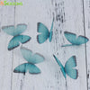 Light blue and gray organza butterfly embellishments scattered on a white wooden surface.