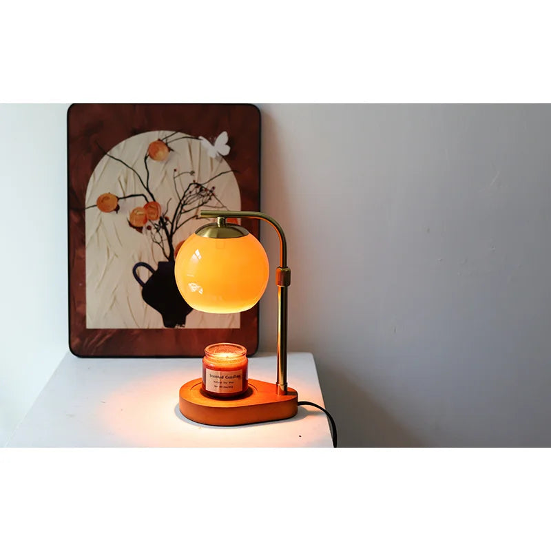 An aromatherapy wax melting lamp with a yellow glass globe and a brass stand, sitting on a white surface.