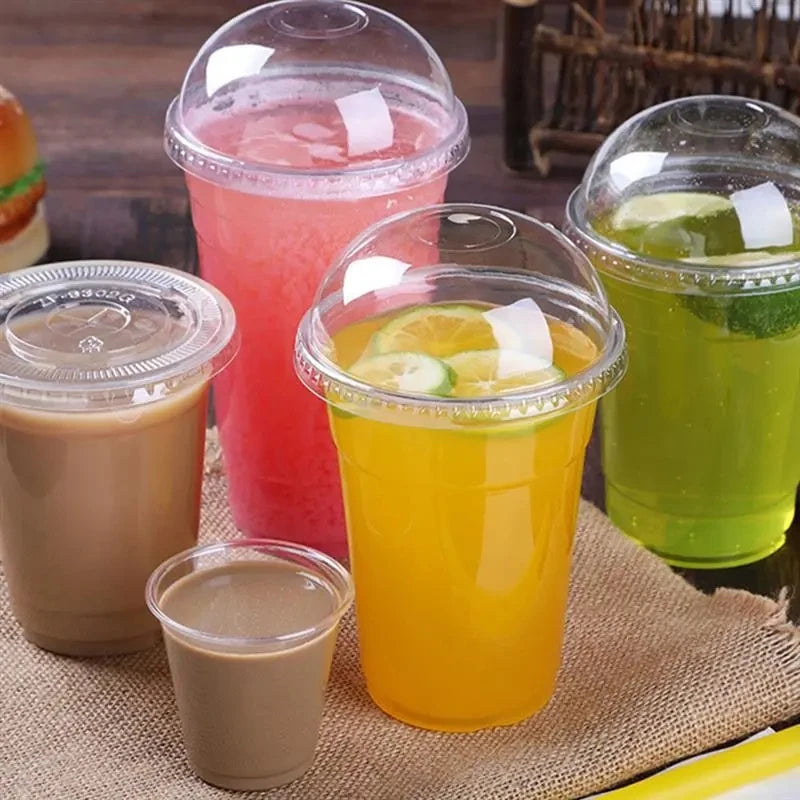 A collection of colorful fruit juices and smoothies in clear disposable plastic cups with lids on a burlap surface.