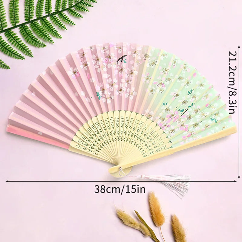 Elegant bamboo folding fan with pink and green floral patterns and a white tassel