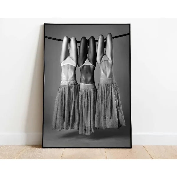 Three women with their hands stretched above their heads wearing sheer gray fabric against a dark background.