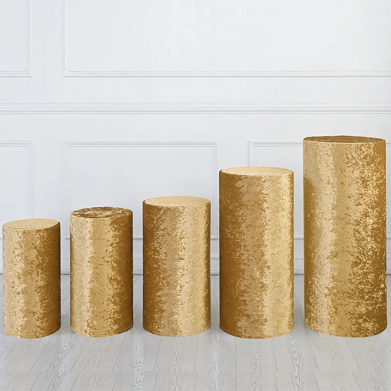 A row of tall, cylindrical gold spandex covers used as stands for weddings and events.