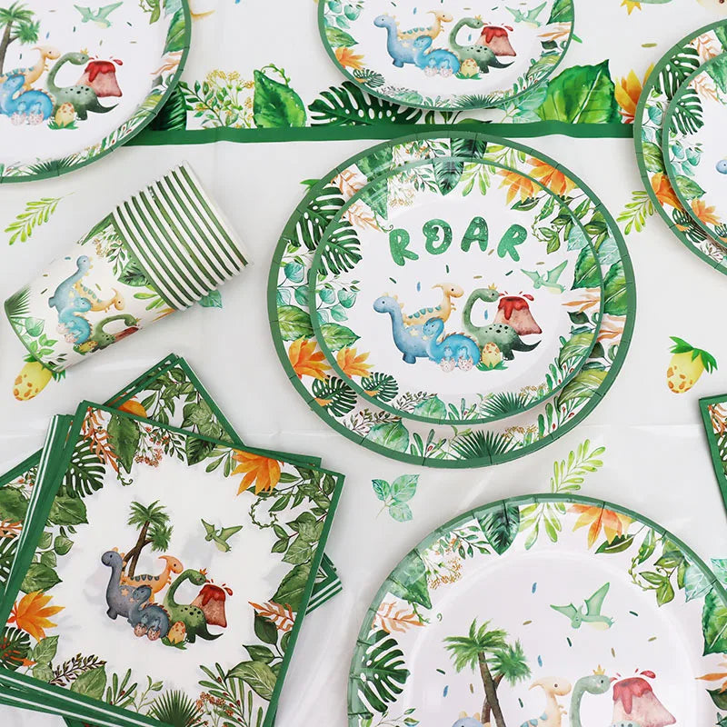 A set of green and white dinosaur-themed disposable tableware including plates, napkins, and a banner.