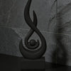 A black, stylized flame sculpture decor is displayed on a dark surface against a gray marble background.