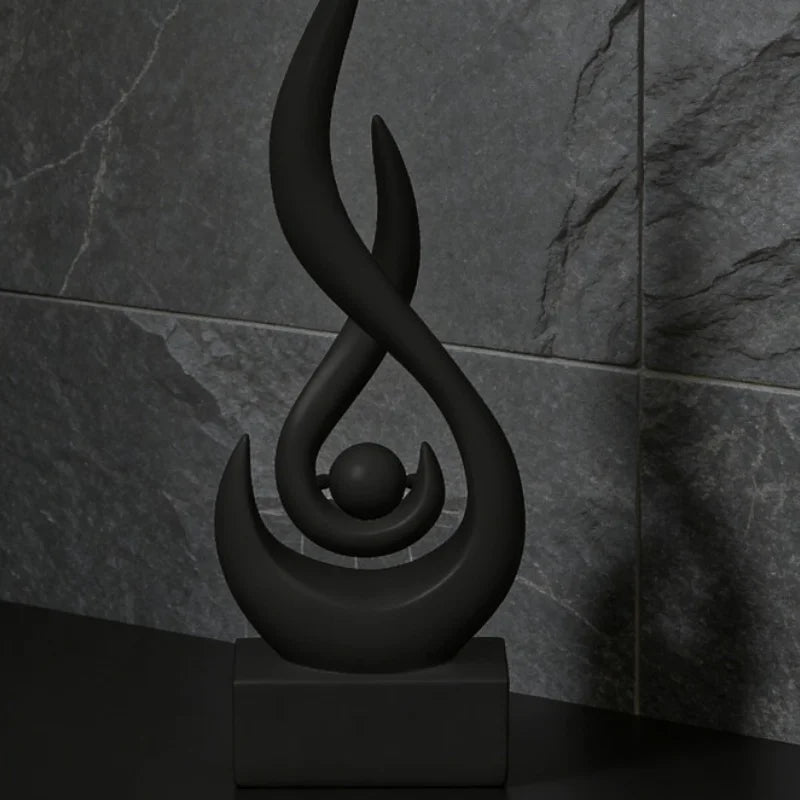 A black, stylized flame sculpture decor is displayed on a dark surface against a gray marble background.