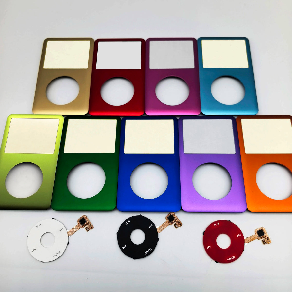 A collection of colorful iPod front faceplates and clickwheel replacement kits arranged in a row.