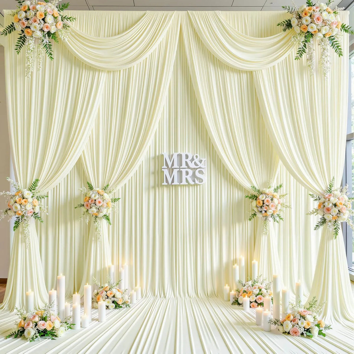 A luxurious cream fabric backdrop with draped curtains and floral accents for an event or wedding.