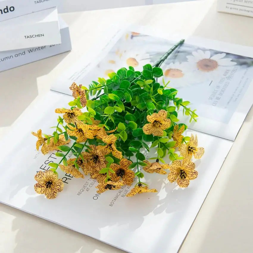 A bouquet of silk eucalyptus and violet artificial flowers displayed on a white card.