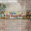 A wooden sign with the text This is My Happy Place painted on it, featuring colorful flowers and greenery.