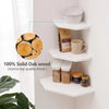 Two white wall-mounted corner shelves displaying natural wood items like a mug and jars.