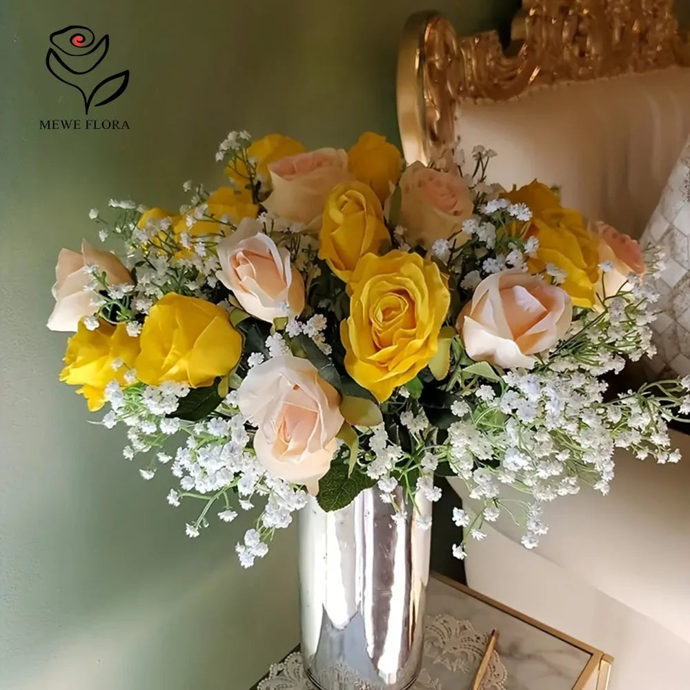 A bouquet of peach and yellow roses mixed with baby's breath flowers in a silver vase.
