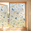 A close-up view of a window with decorative privacy film featuring butterflies and foliage.