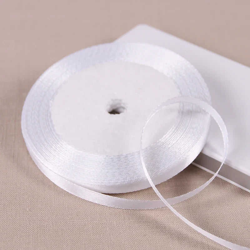 A roll of white satin ribbon on a spool, ready for gift wrapping or DIY crafts.