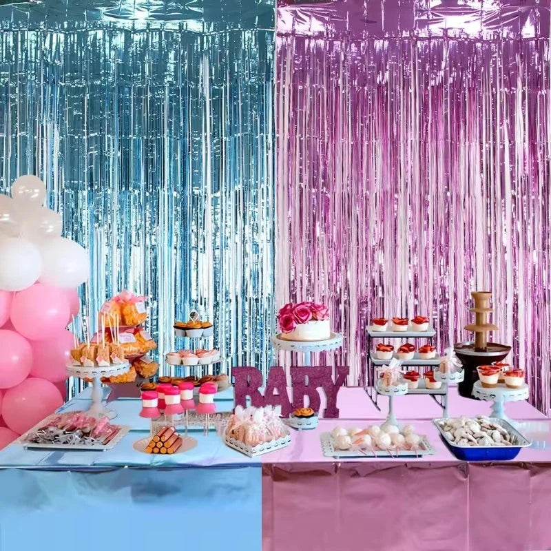A vibrant party backdrop featuring iridescent blue and purple metallic foil tinsel fringe curtains with pink balloons and a d