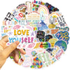 A hand is touching a colorful circular graphic made of inspirational words and designs.