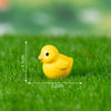 A small yellow duck figurine placed on green grass with measurement lines.