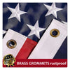 Close-up of a white embroidered American flag with brass grommets on a dark blue background.