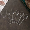 A collection of clear plastic disposable spoons arranged on a dark surface.
