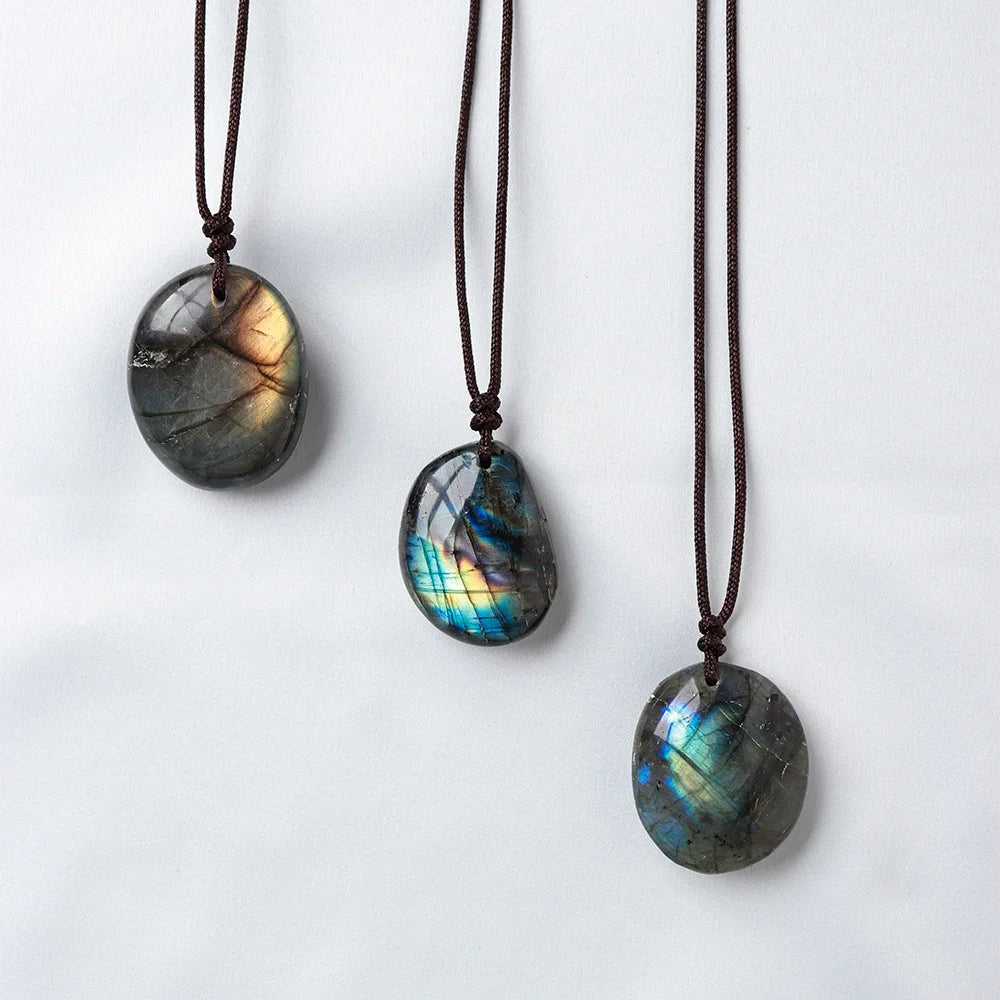 A dark, oval labradorite gemstone pendant on a brown leather cord.